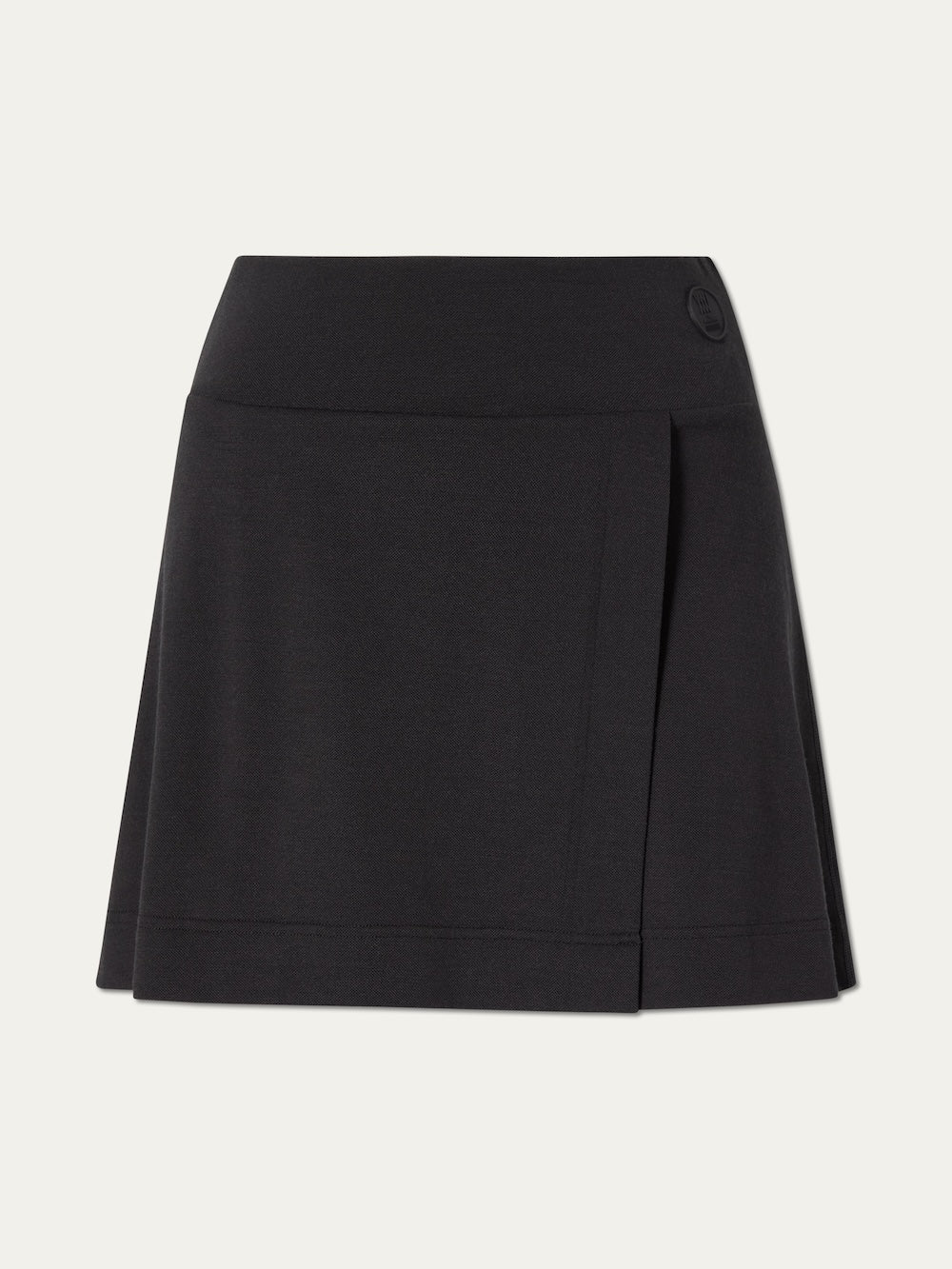 The Medalist Piqué Skirt Women by We Norwegians is a black, knee-length A-line skirt in smooth merino wool with a wide waistband, subtle front pleat, and round button detail—a refined update to the classic tennis skirt.