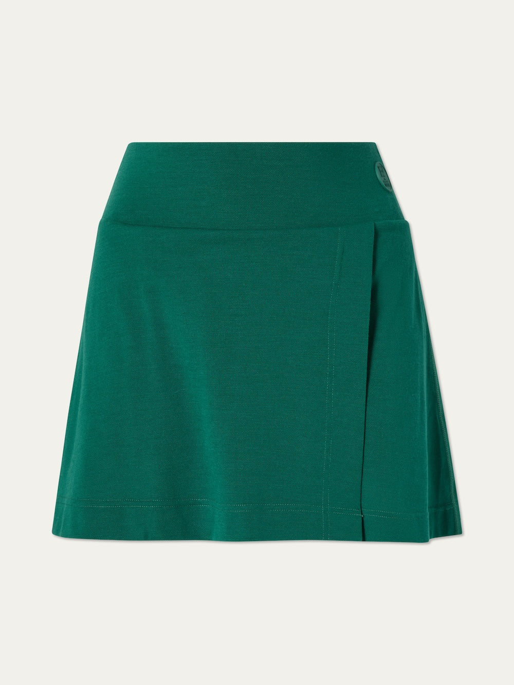 The Medalist Piqué Skirt Women by We Norwegians is a green, A-line merino wool skirt with a wide waistband and subtle front pleat, shown against an off-white background.