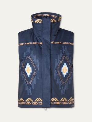 The We Norwegians Pioneer Padded Vest for women is a sleeveless navy blue vest with a high collar, tan and light blue geometric patterns, a large diamond digital print on the front, and border accents along the edges.