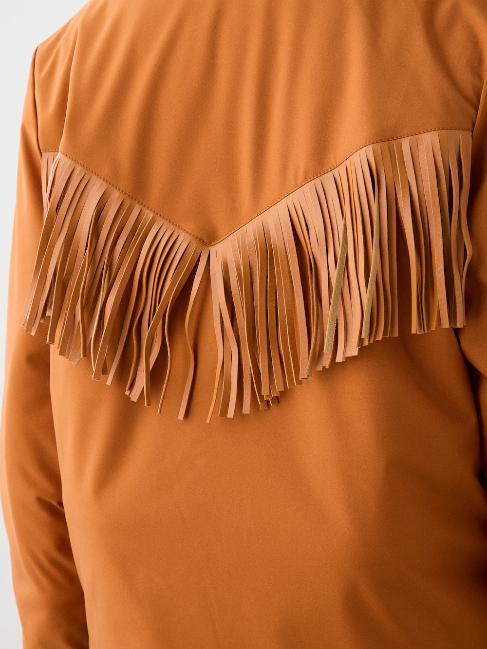 Close-up of the back of the We Norwegians Western Ski Jacket women in tan, featuring decorative fringe along the upper yoke and matching strips for a cowboy-inspired look with subtle alpine detailing.
