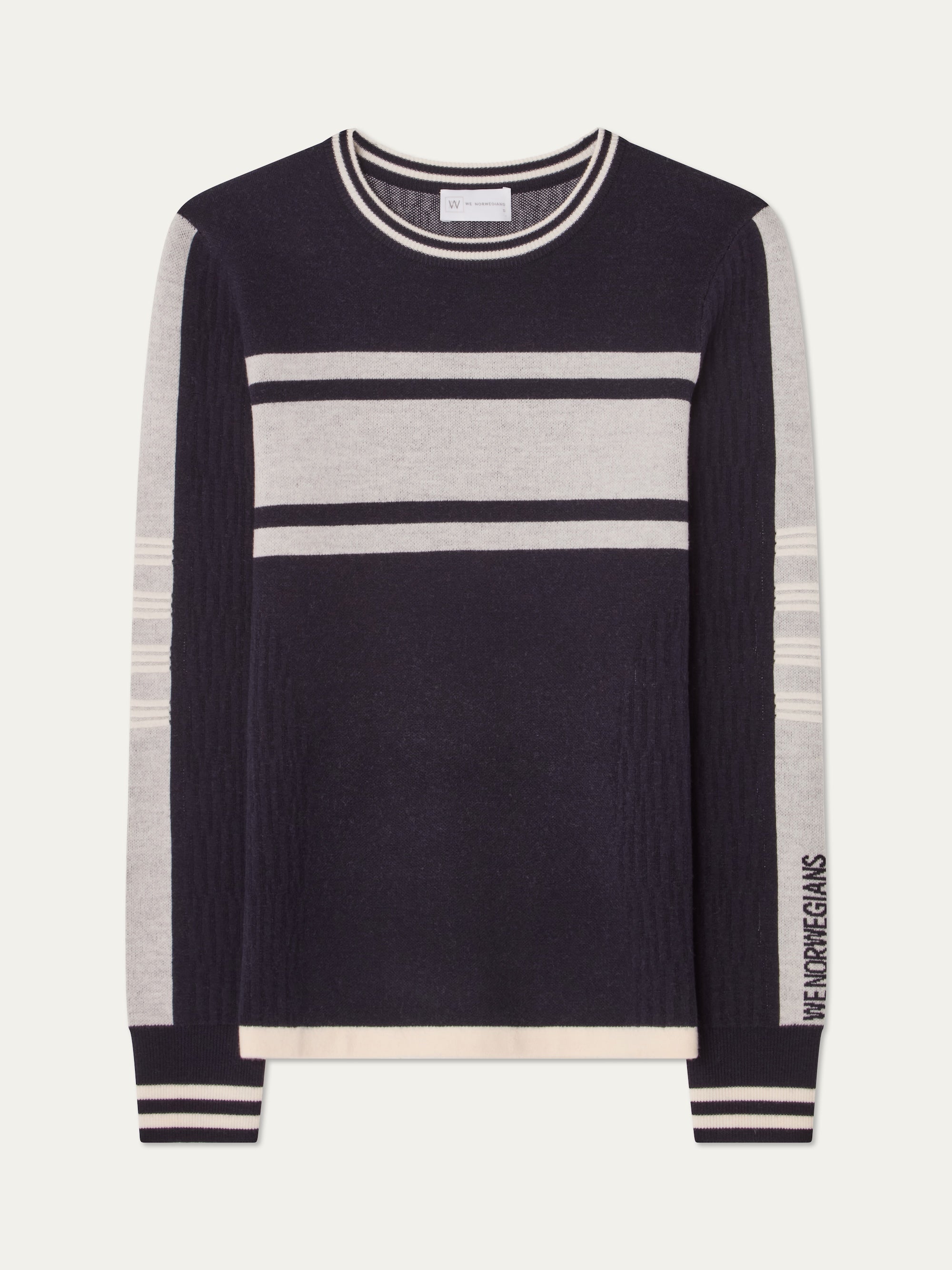 The We Norwegians Rocky Ski Sweater for women is a navy and light gray merino wool sweater with horizontal chest and sleeve stripes, "WE NORWEGIANS" text on the sleeve, and contrasting trim at the neck, cuffs, and hem.