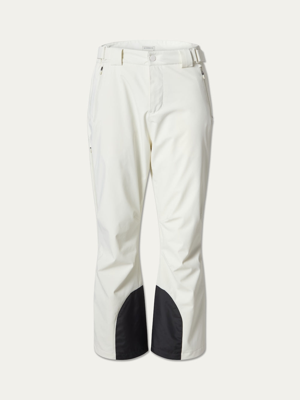 The We Norwegians Hammerfest Ski Pant men are white, 4-way stretch ski pants with a straight leg fit, featuring black reinforced patches on the inner lower legs and zippered pockets near the hips.