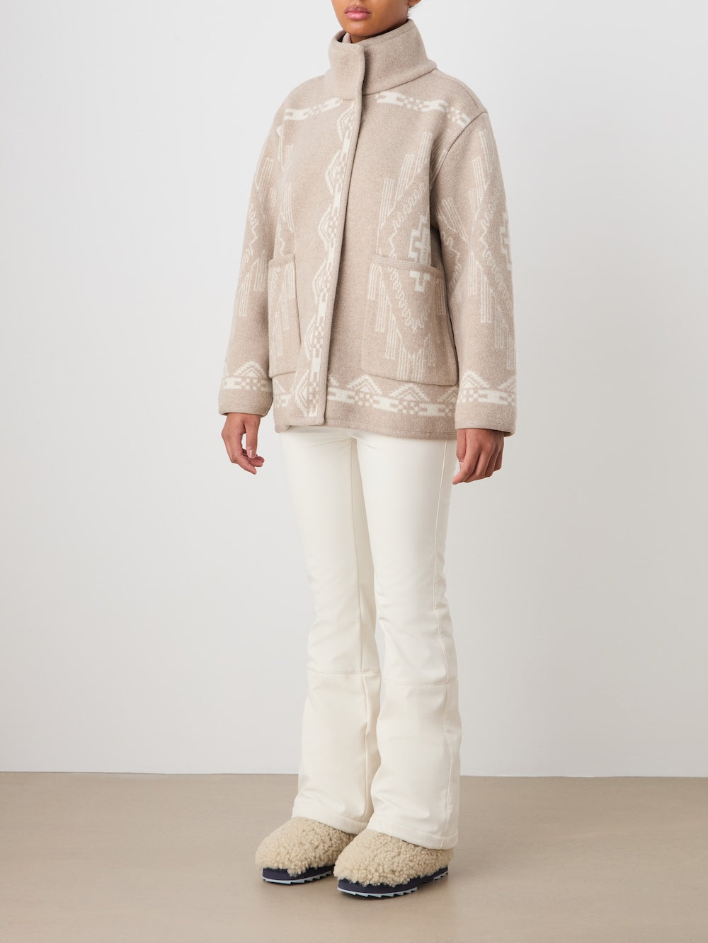 A woman wearing a We Norwegians Pioneer Jacket women - Pre Spring 26 and white pants.