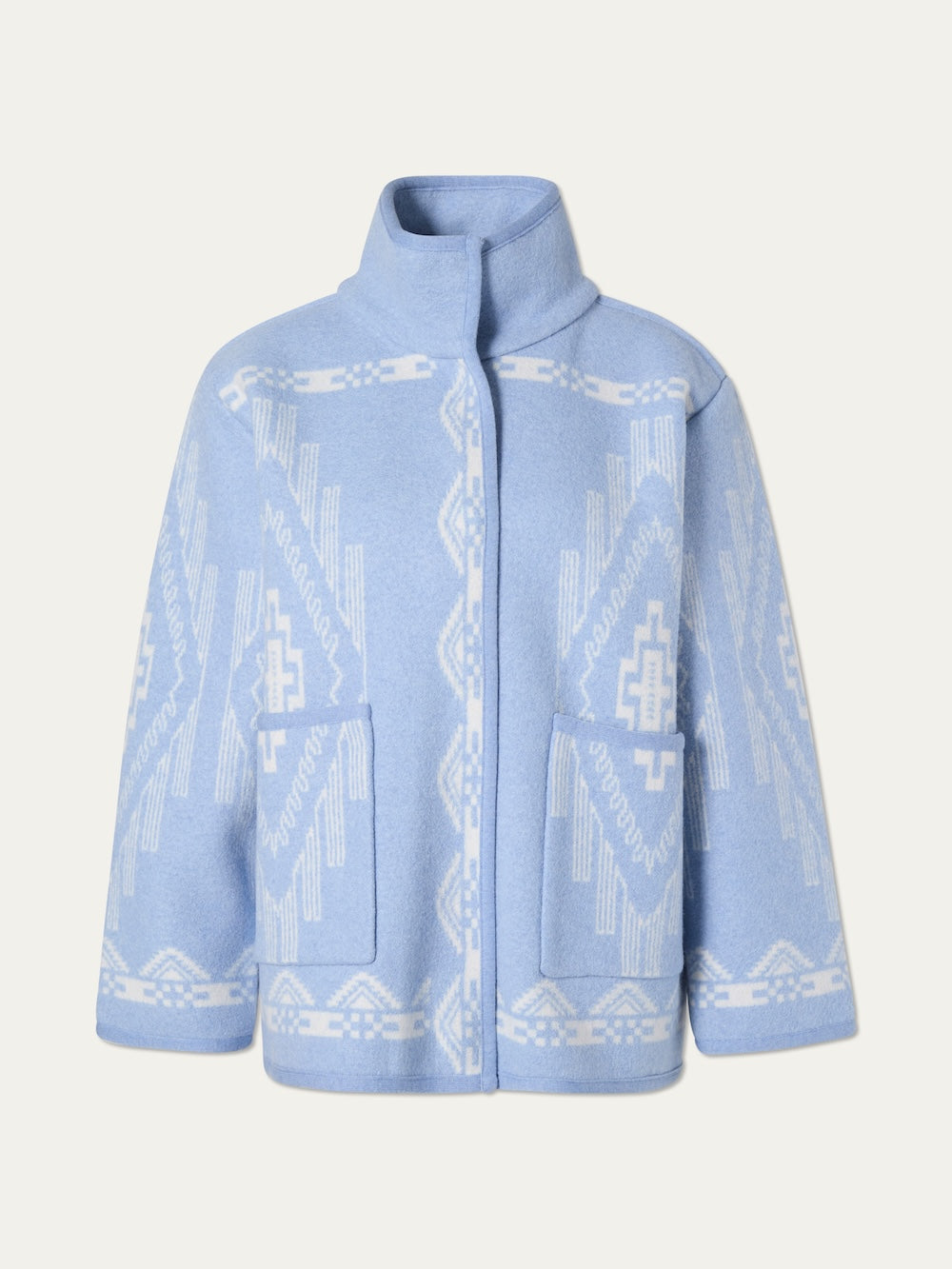 The Pioneer Jacket women - Pre Spring 26 by We Norwegians is an oversized light blue boiled wool jacket with white geometric patterns, stand-up collar, long sleeves, large front pockets, and a concealed closure—crafted for softness.