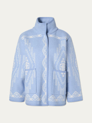 The Pioneer Jacket women - Pre Spring 26 by We Norwegians is an oversized light blue boiled wool jacket with white geometric patterns, stand-up collar, long sleeves, large front pockets, and a concealed closure—crafted for softness.