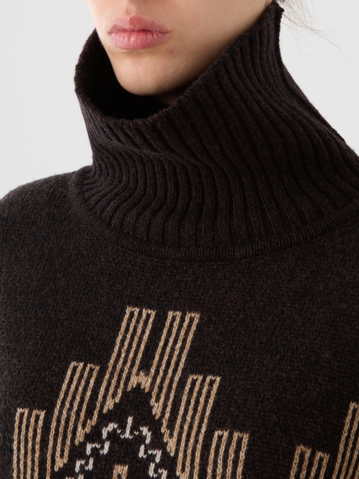 We Norwegians Pioneer Sweater women in dark brown jacquard wool, featuring a turtleneck and a geometric beige and white pattern on the chest.