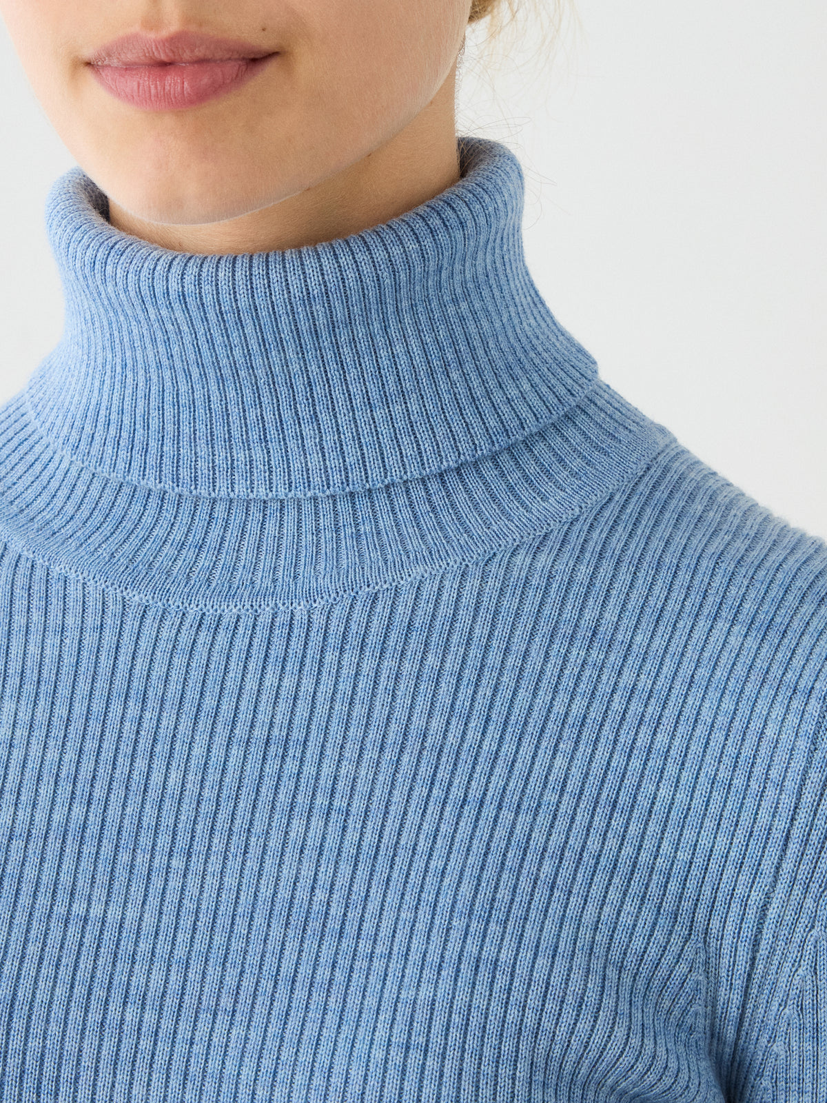 A person wearing the We Norwegians Geilo TurtleNeck for women in light blue, shown from the shoulders up with only the lower half of the face visible.
