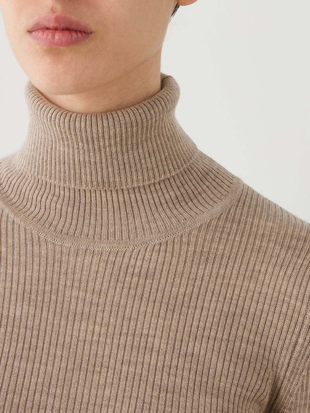A close-up of a person wearing the We Norwegians Geilo TurtleNeck women sweater, showing their neck, part of their face, and upper chest against a plain background.