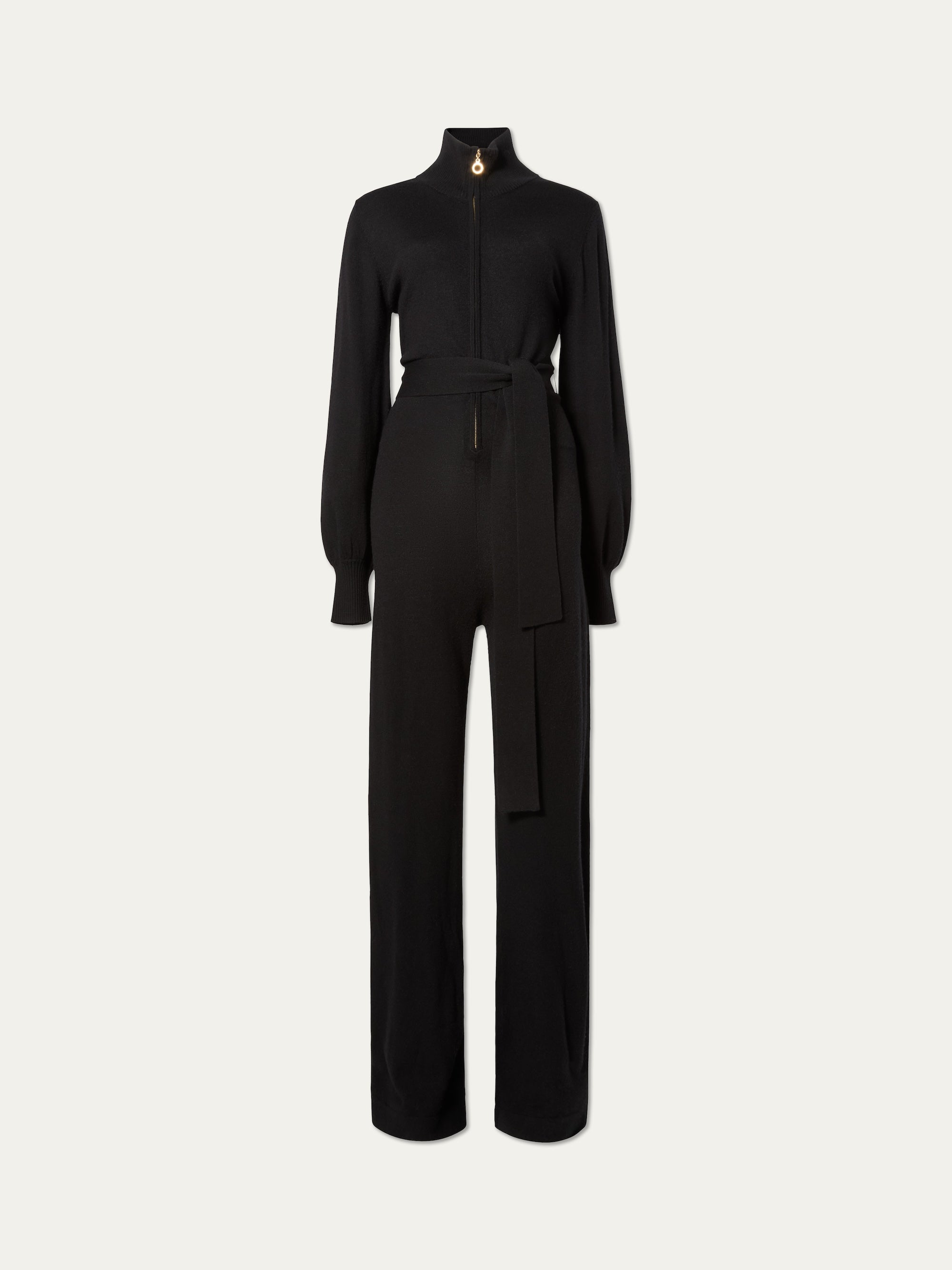 The We Norwegians Geilo Jumpsuit women in black features a high collar, front zipper, wide-leg pants, fabric waist belt, and puffed cuffs—an elegant mountain resort outfit shown against a plain light background.
