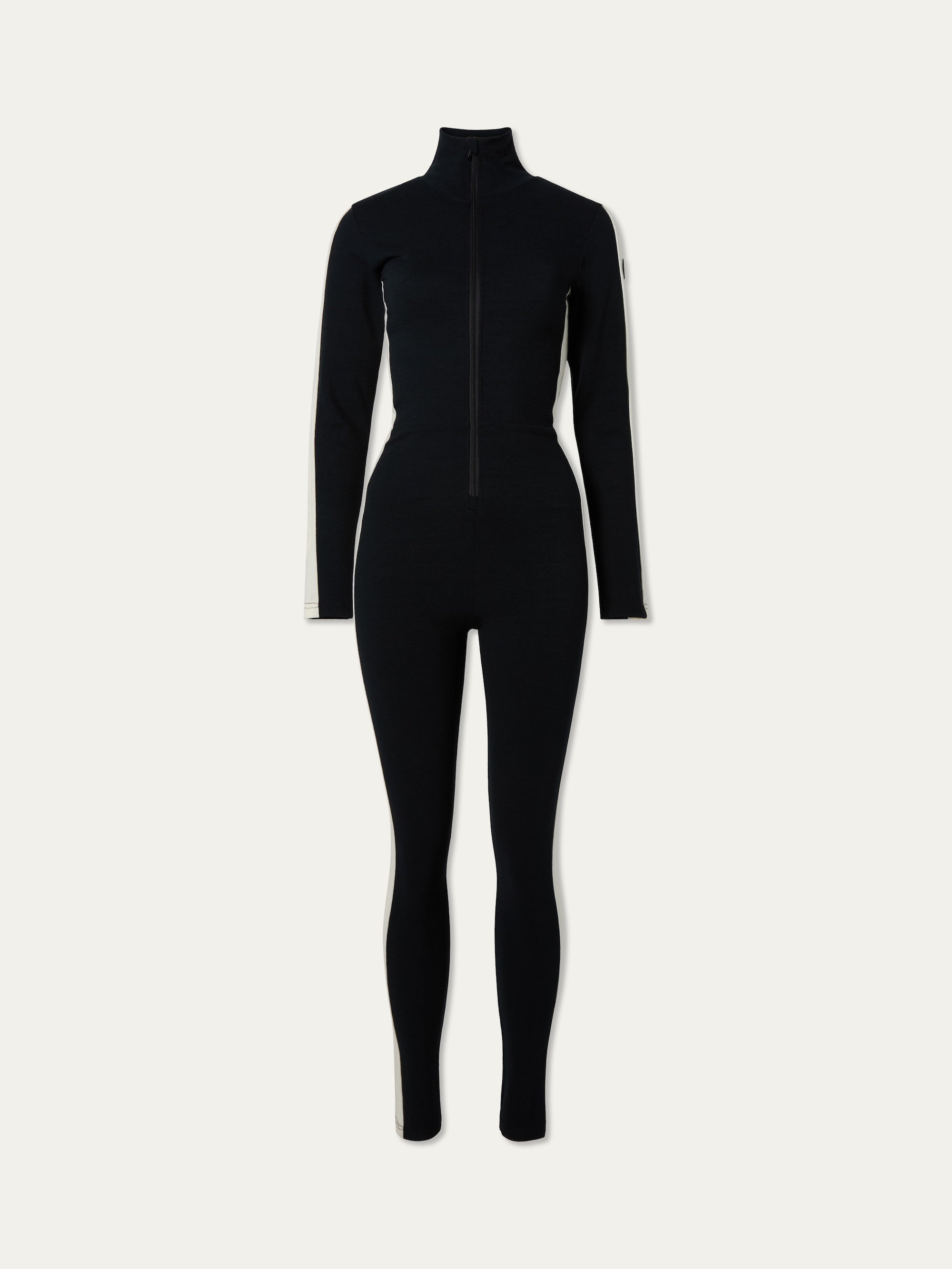 The We Norwegians Voss Jumpsuit women: a black, full-length merino base layer with long sleeves, high collar, front zipper, and white sleeve and leg stripes—sleek and perfect for skiing—shown on a plain light background.