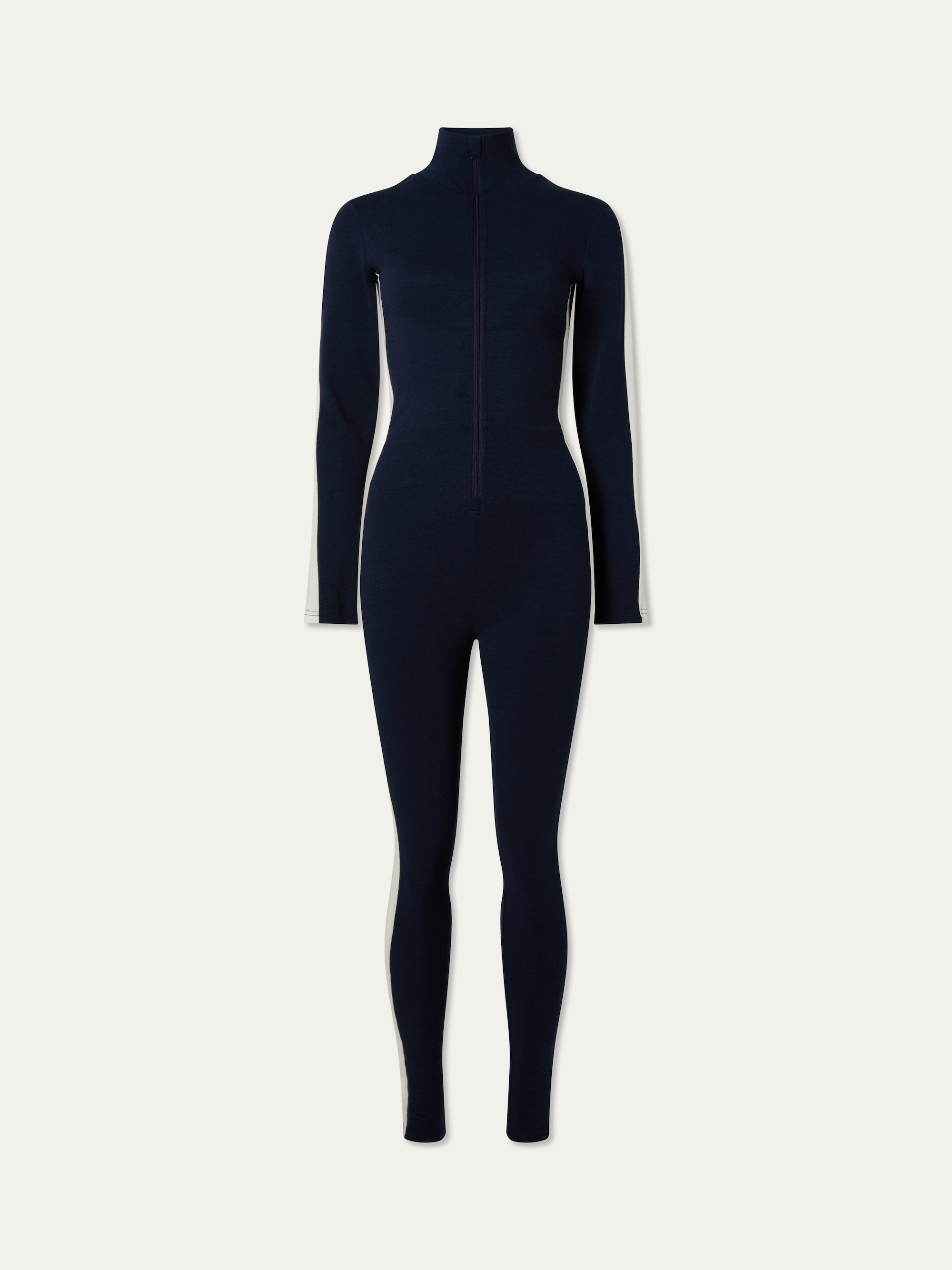 The Voss Jumpsuit women from We Norwegians is a navy, full-length, form-fitting retro style with long sleeves, a high neckline, front zipper, and white side panels—ideal ski loungewear.