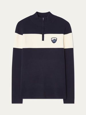 The We Norwegians Holmenkollen ZipUp men is a navy blue vintage ski sweater featuring a white chest stripe, half-zip collar, and a shield logo on the left chest—blending style and comfort for any occasion.