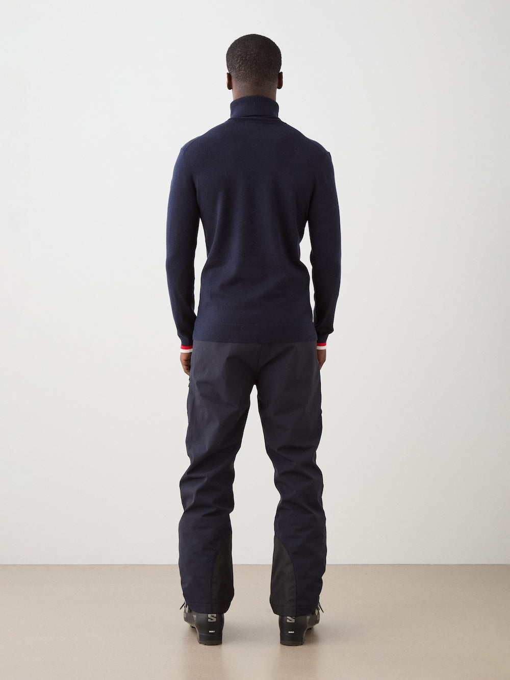 We Norwegians | FW25 | Mens Freebird Turtleneck | Person wearing a navy turtleneck with red and white stripes in the front and matching pants on a plain background