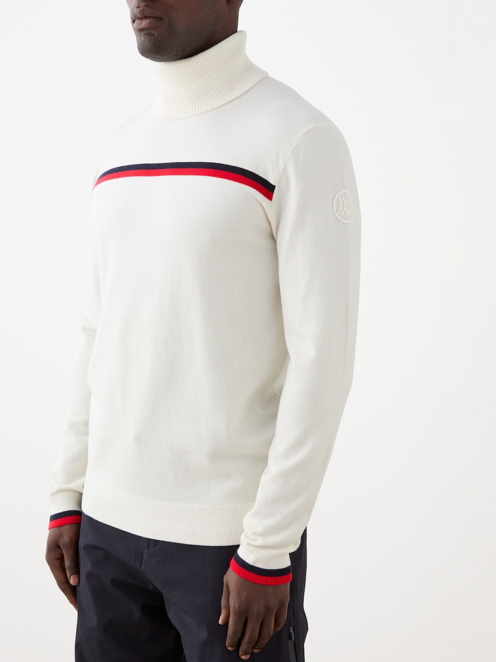 White turtleneck sweater with red and blue stripes worn by a person on a white background
