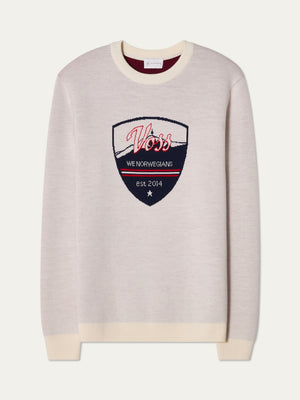 The We Norwegians AfterSki CrewNeck men’s sweater is cream-colored merino wool with white cuffs and hem, and a large chest patch reading “Voss, WE NORWEGIANS, est. 2014”—a perfect après ski choice.