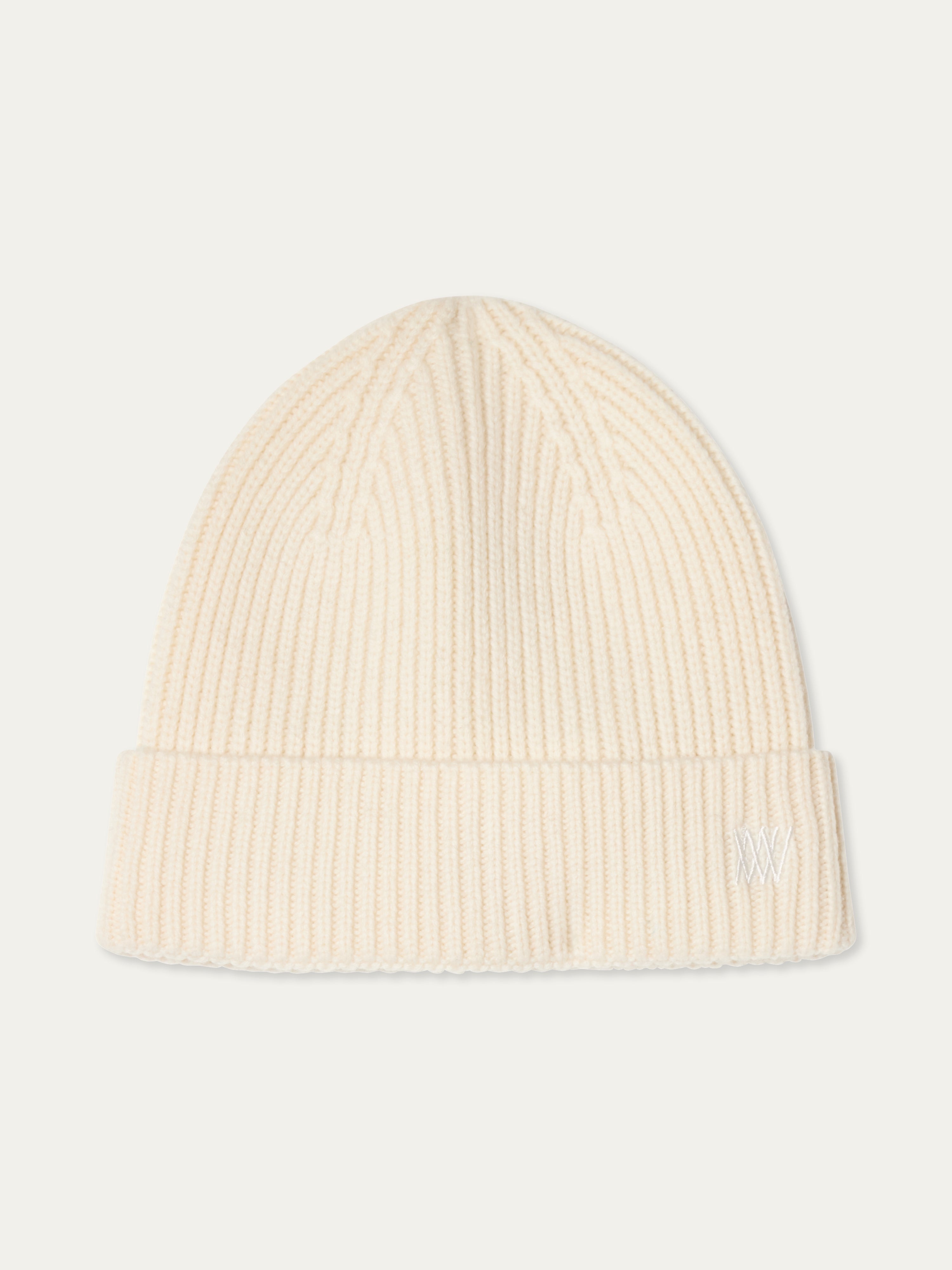 The We Norwegians Dal Hat is a cream-colored ribbed knit beanie in classic Scandinavian style, featuring a folded brim and a small white embroidered logo on the front.