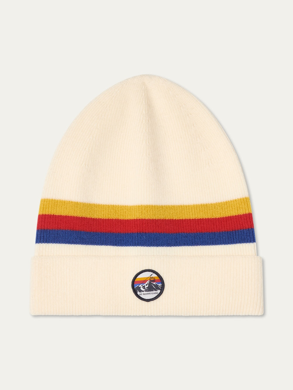 The We Norwegians FreeBird Hat is a cream-colored knit beanie with red, orange, and blue stripes near the top, a folded brim, and a circular patch featuring a mountain and sunset design.