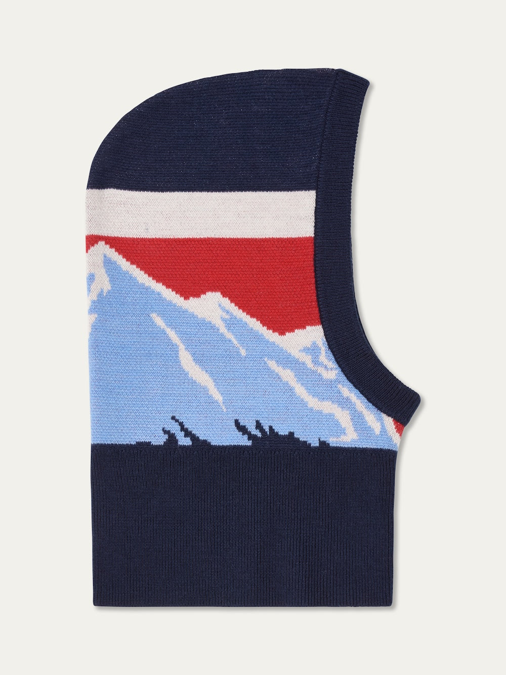 The We Norwegians Snowmass Balaclava is a flat knit design with blue and white mountains, a red and white sky, and a navy background. The face opening is positioned on the right side.
