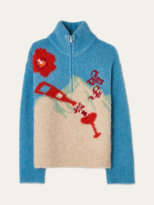 The We Norwegians WN x Markarian Bouclé Sweater for women is a limited edition, fuzzy blue and cream half-zip with Italian bouclé yarn, showcasing a red ski lift, red flower, green mountains, and “Après Ski” on the front.