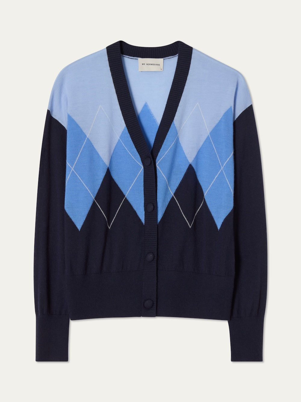 The Bandit Cardigan Women by We Norwegians is a luxury knit button-up with a deep V-neck, navy base, and oversized light and dark blue argyle diamond pattern on the chest and sleeves.