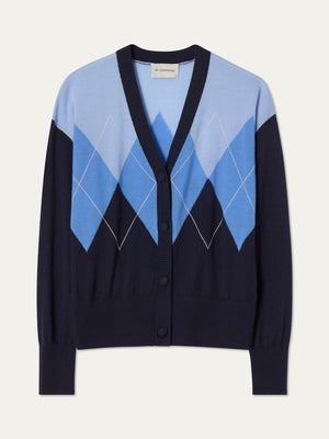 The Bandit Cardigan Women by We Norwegians is a luxury knit button-up with a deep V-neck, navy base, and oversized light and dark blue argyle diamond pattern on the chest and sleeves.