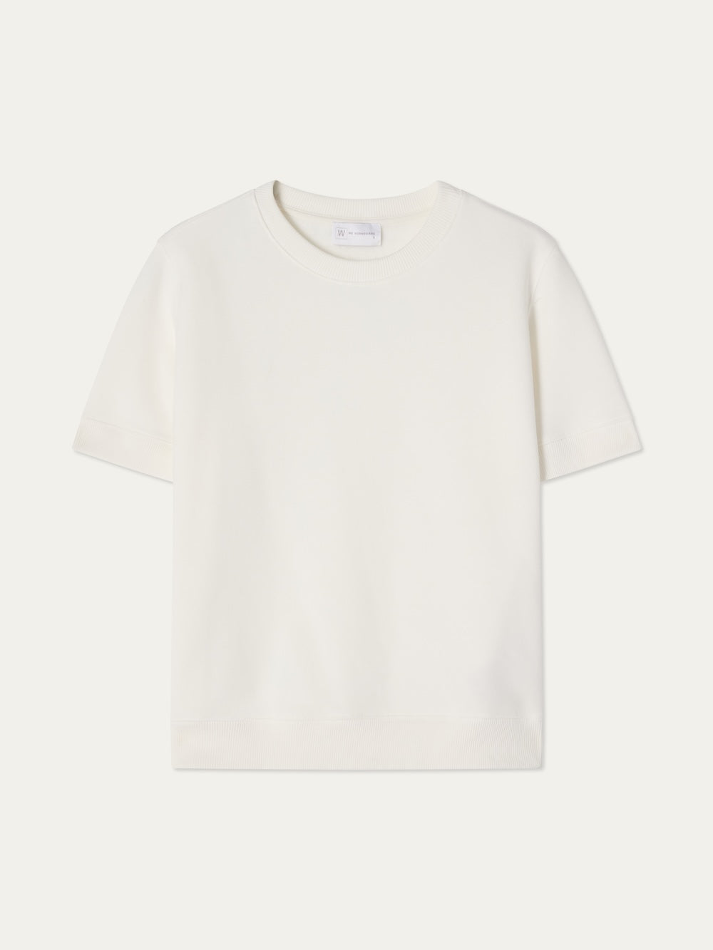 The We Norwegians Bounce Top Women is a plain white, sporty short-sleeve crew neck displayed against a light background. Its simple, logo-free cotton design offers timeless versatility.