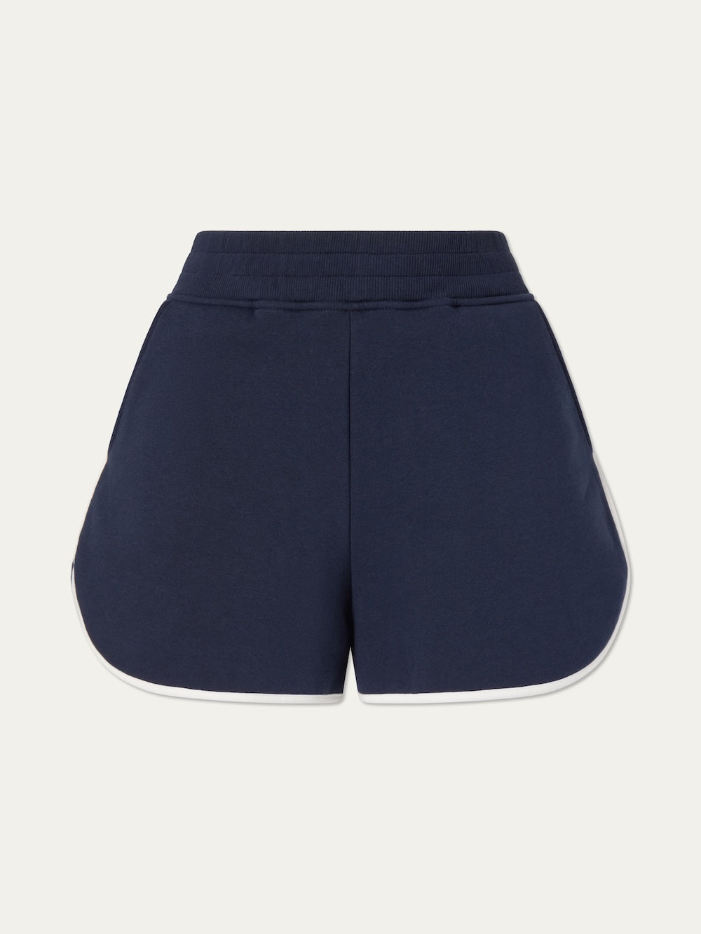 The We Norwegians Bounce Shorts Women are navy blue athletic shorts with white trim, a curved hem, and an elastic waistband, inspired by classic 70s tennis style and shown against a plain white background.
