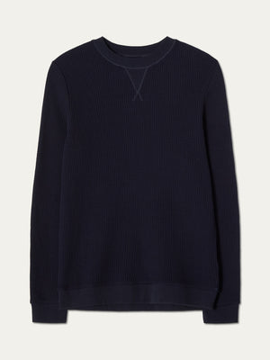 The We Norwegians Waffle Crewneck Men is a relaxed-fit, long-sleeve, dark navy cotton sweater with ribbed collar, cuffs, and hem, shown flat on a plain light background.