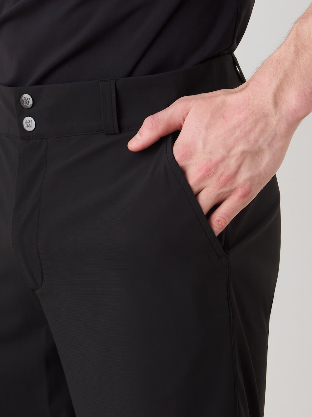 A person is shown from the midsection, wearing We Norwegians Albatross Shorts Men in black with a matching black shirt, right hand resting in the shorts' front pocket. Only their midsection and hand are visible.