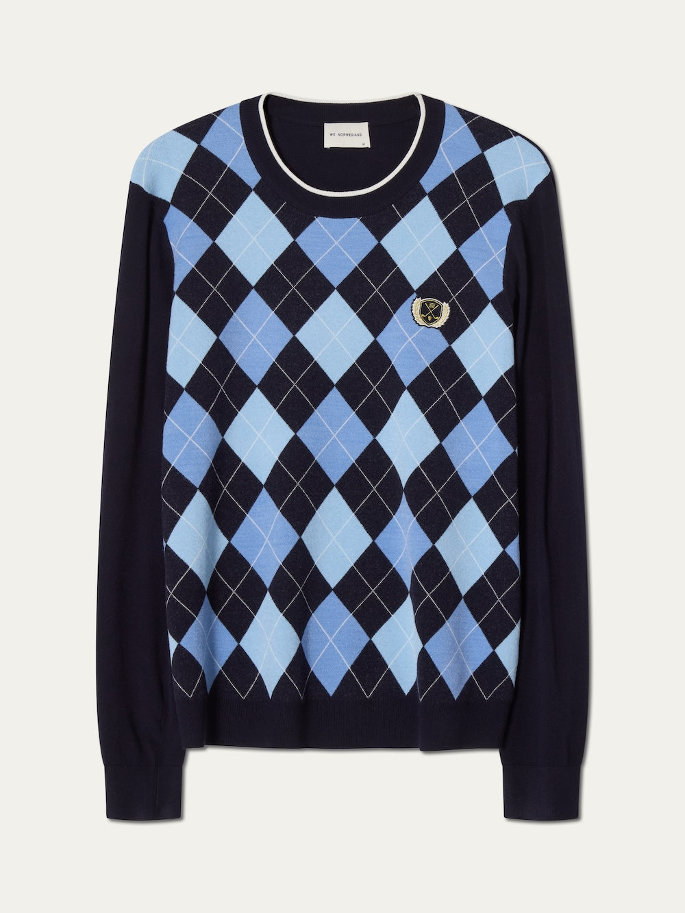 The We Norwegians Fairway Sweater Men is a navy blue golf sweater featuring a light and dark blue argyle knit front, long sleeves, and an embroidered chest crest. Lightweight and breathable, it's ideal for cool days on the course.