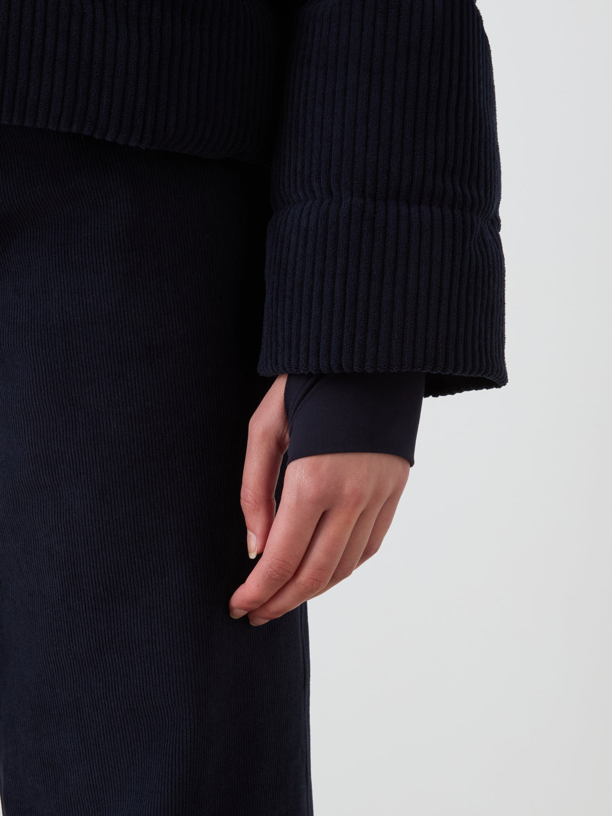 A person stands against a white background, wearing the We Norwegians Britt Ski Jacket Women and matching pants, channeling a sustainable ski wear look.
