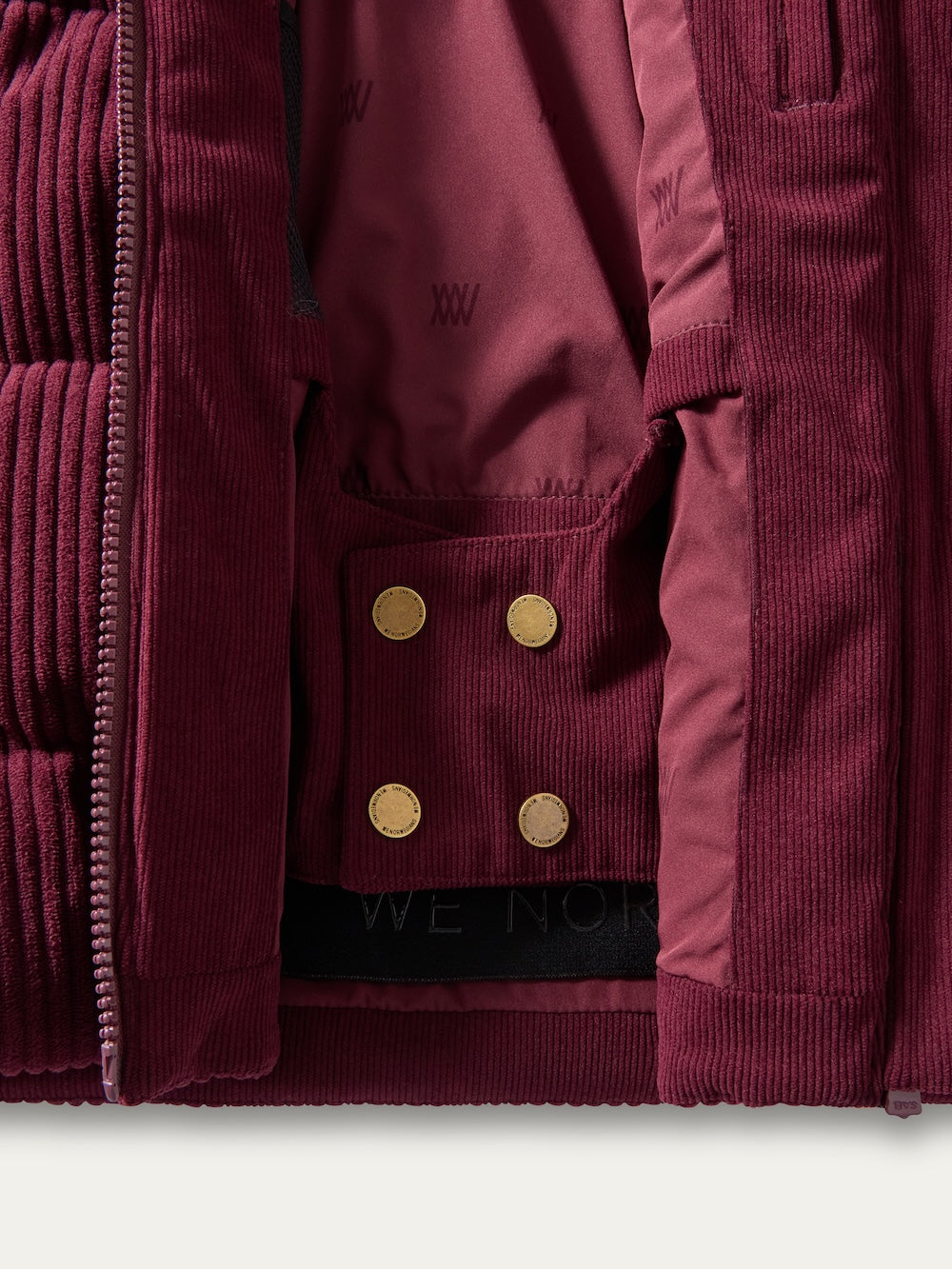 Close-up of the inside of the We Norwegians Britt Ski Jacket Women, featuring gold snap buttons, a patterned lining, and stitched details.
