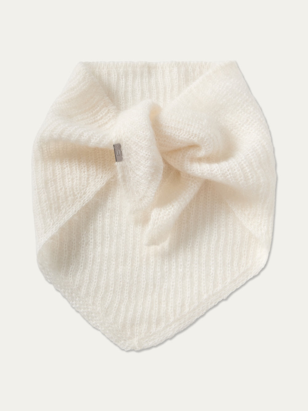 The We Norwegians Pudder Scarf is a soft, white knit accessory with a ribbed texture, folded in a triangular shape and tied at the front. Featuring a small rectangular tag on one side, this designer winter scarf is ideal for adding elegant warmth to your cold-weather outfits.