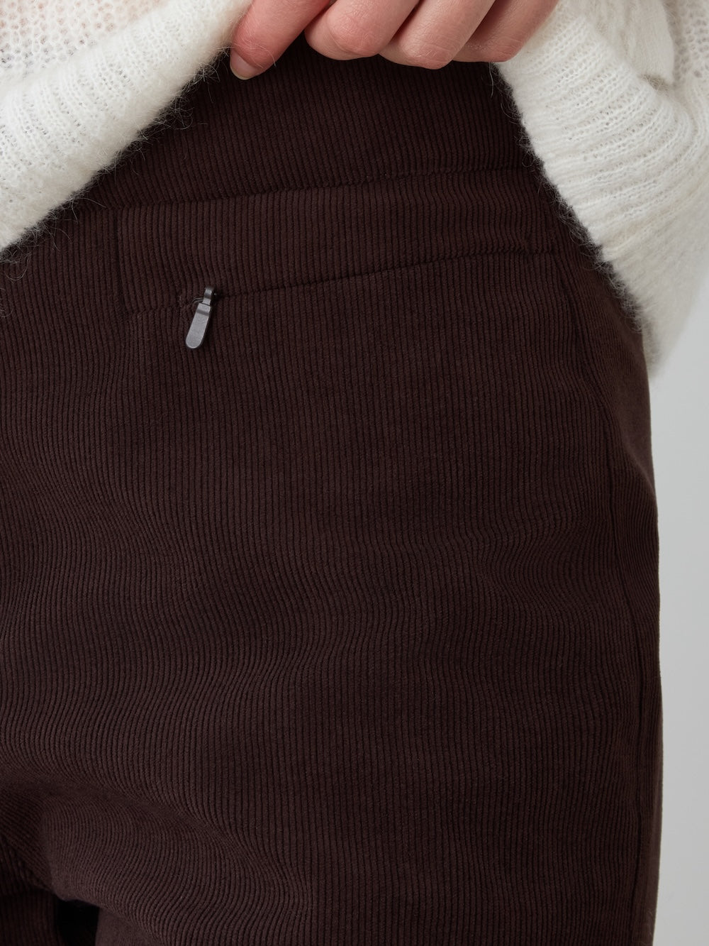 A person wearing We Norwegians’ Britt Palazzo Ski Pant for women, featuring high-waisted baby corduroy fabric and a zipper pocket detail, shown from the waist down.