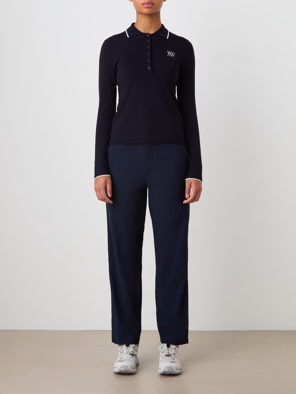 Person wearing a navy blue long-sleeve polo shirt and pants on a light background