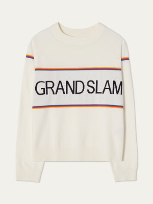 The Grand Slam Sweater Women by We Norwegians is a white knit with “GRAND SLAM” in bold black letters, yellow, orange, and blue stripes, long sleeves, and a crew neck—ideal for a vintage-inspired après sport look.