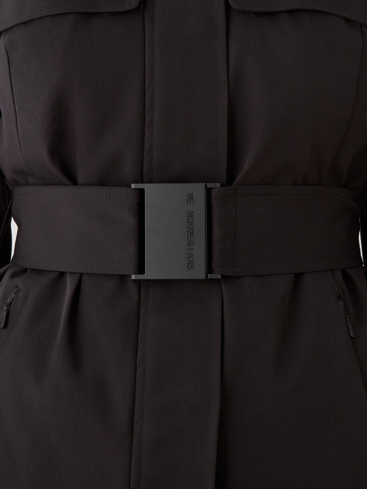A close-up of the black Finse Ski Jacket Women by We Norwegians, featuring a wide belt with a rectangular buckle engraved “THE INCREDIBLE DAYS,” smooth texture, and visible seams—perfect for any ski ensemble.