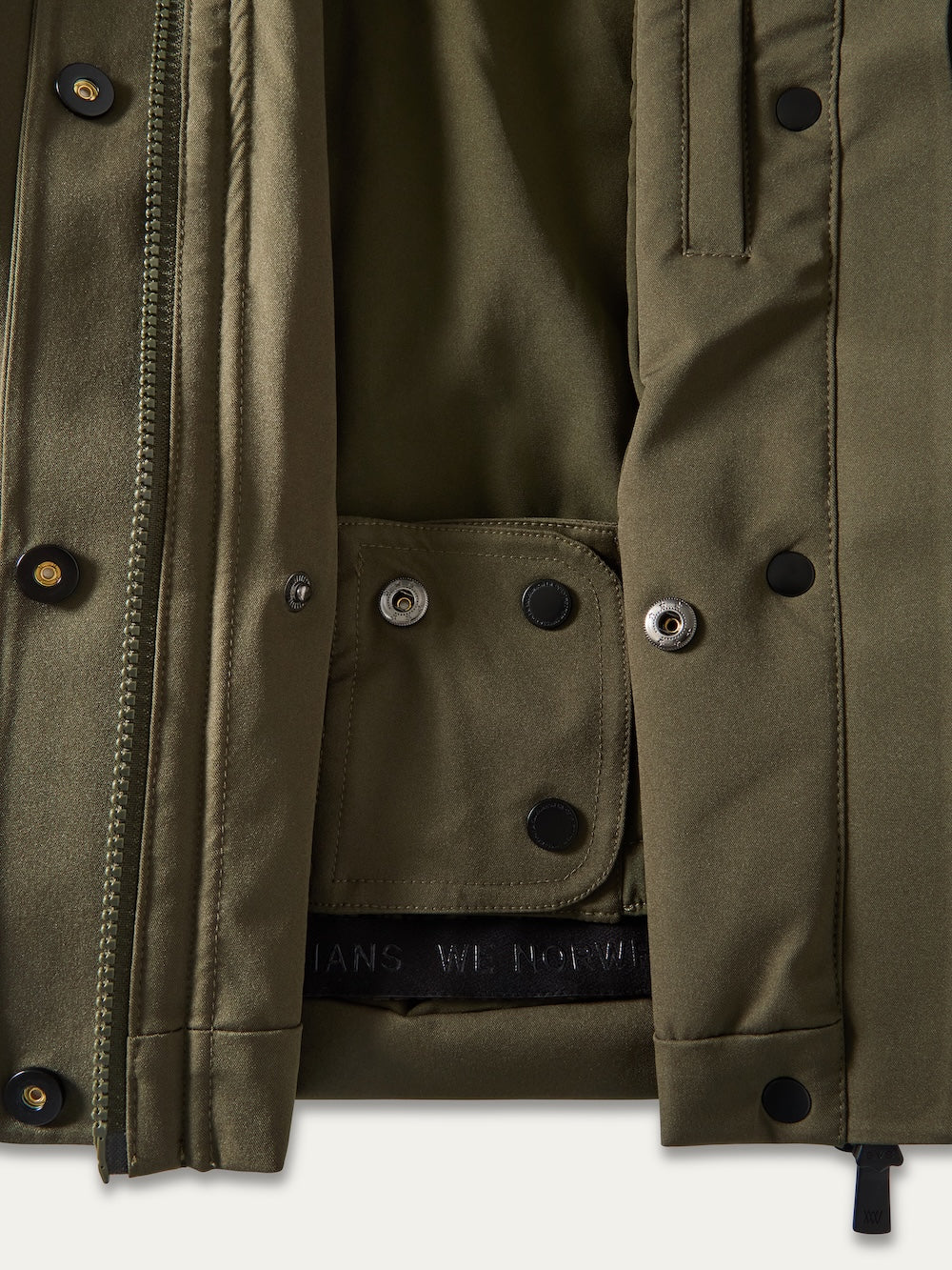 Close-up of an olive green Finse Ski Jacket Women by We Norwegians, highlighting its smooth inner lining, button closures, detailed stitching, and a black embossed label—ideal for a sleek ski jacket look.