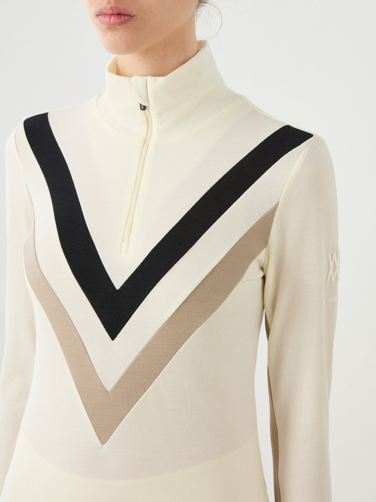 We Norwegians Voss Chevron ZipUp Women off-white merino wool zip-up mock neck top featuring a black and beige chevron pattern across the chest.