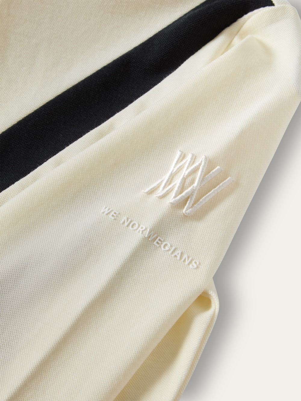 Close-up of a white We Norwegians Voss Chevron ZipUp Women featuring a black stripe on the arm and an embroidered logo.
