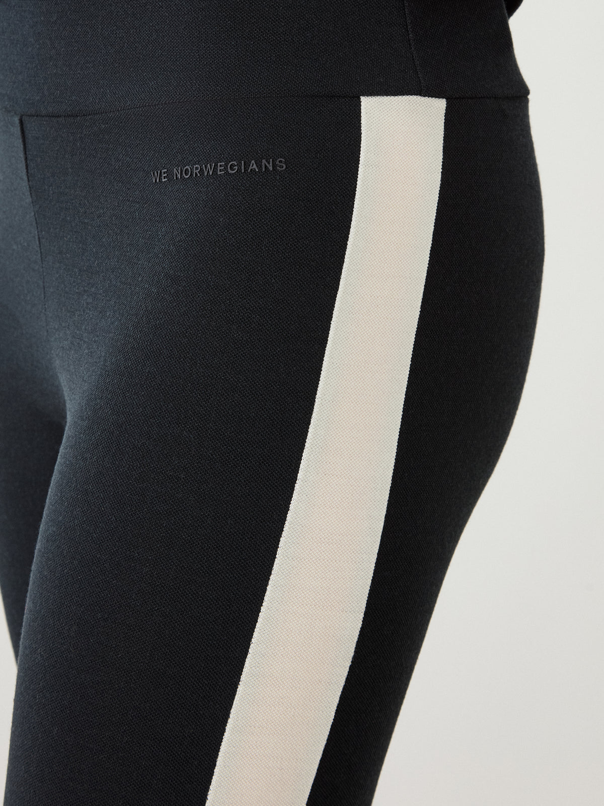 We Norwegians Voss Leggings Women, black and breathable with a wide cream-colored stripe running down the outer thigh.
