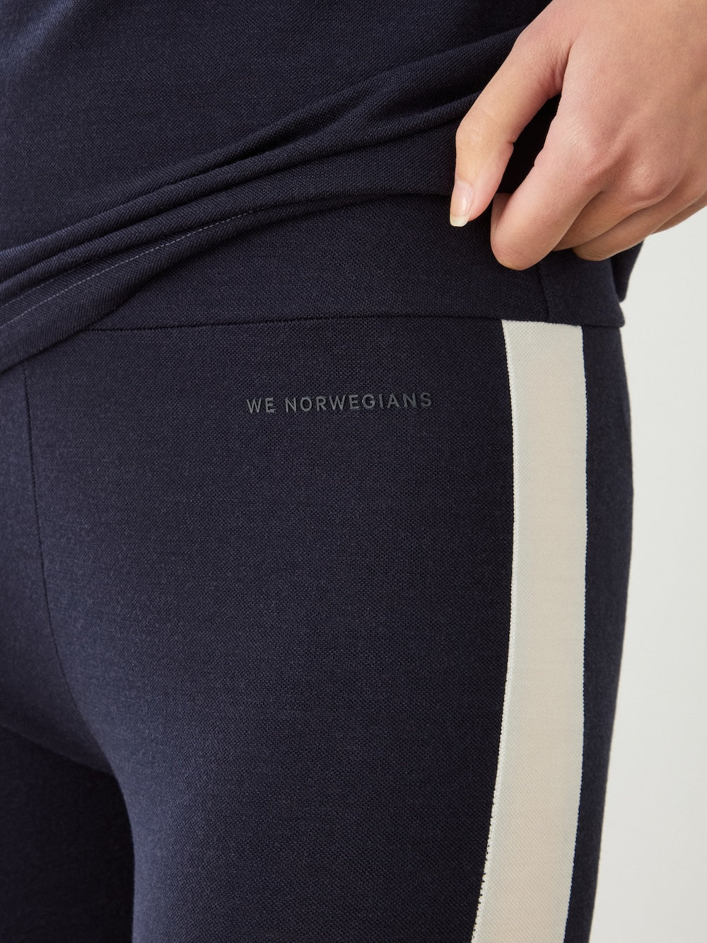 Close-up of navy blue Voss Leggings Women with a vertical white stripe down the side and the text “WE NORWEGIANS” printed on the hip.