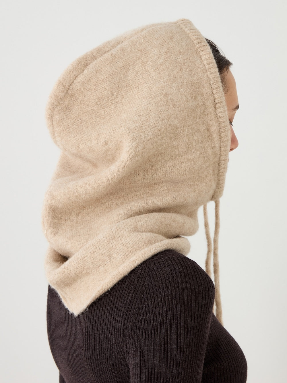 A person in a brown ribbed sweater wears the We Norwegians Norefjell Hood, shown in profile against a plain light background.