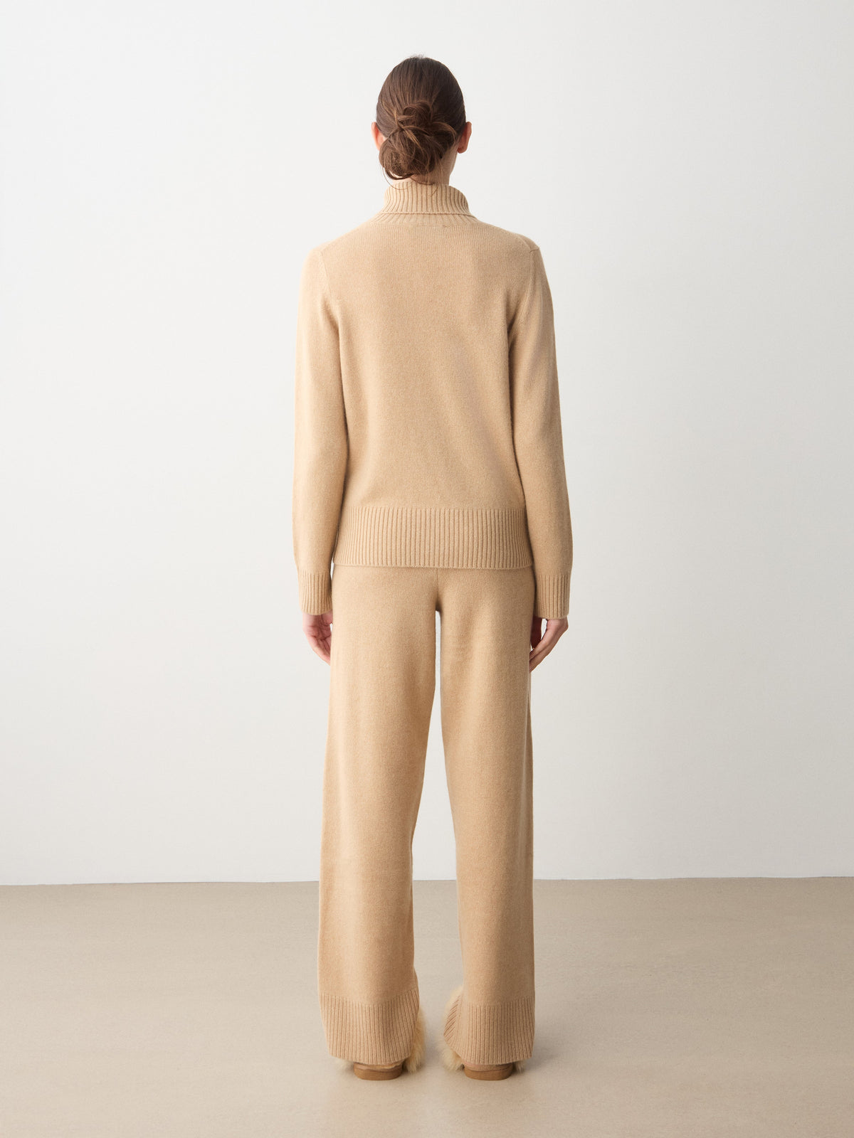 Back view of a person wearing a beige Monogram Cashmere Sweater Women and matching wide-leg trousers.