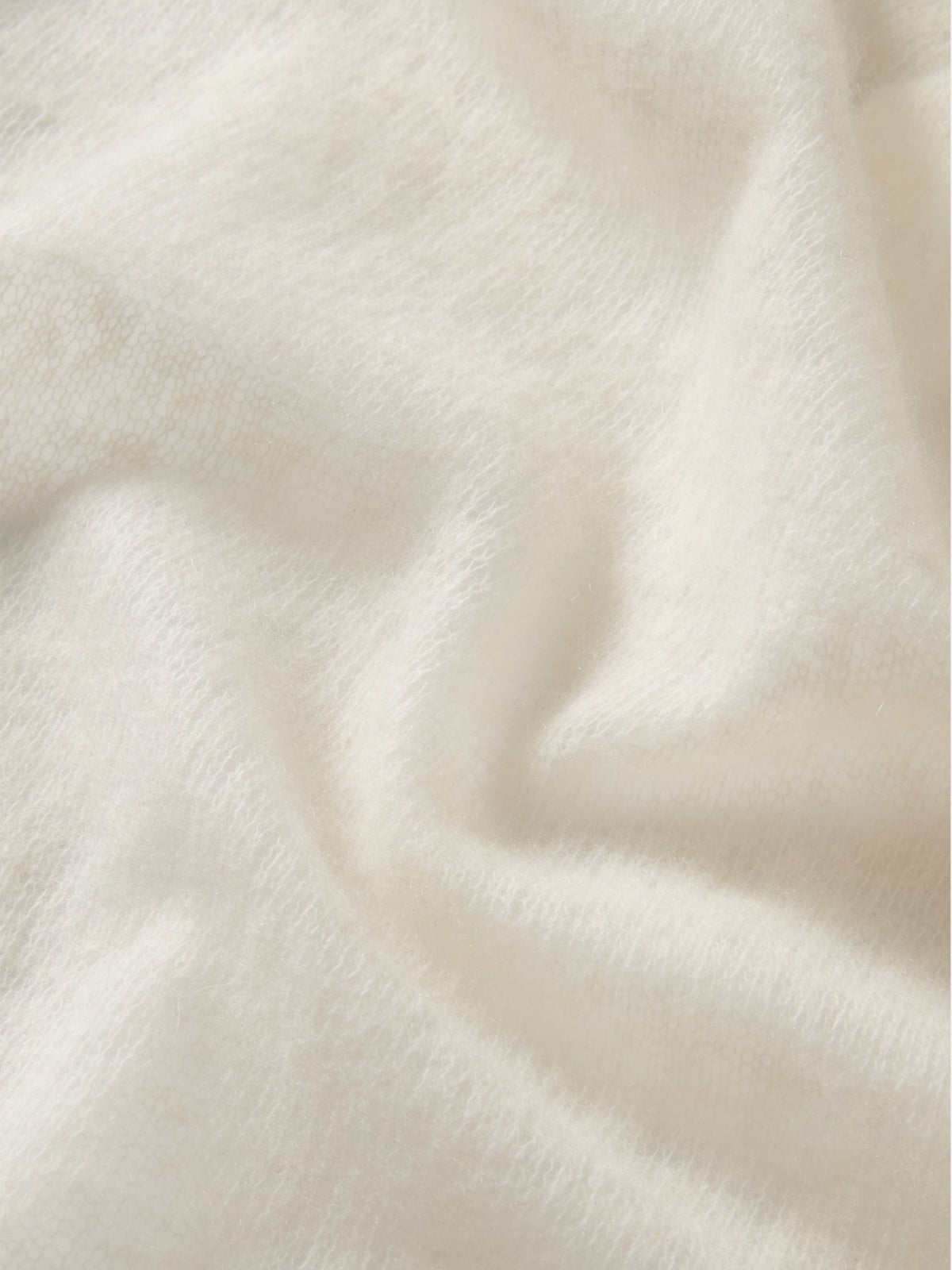 Close-up of a featherlight, cream-colored We Norwegians Monogram Cashmere Scarf with a subtle, repeating monogram pattern.