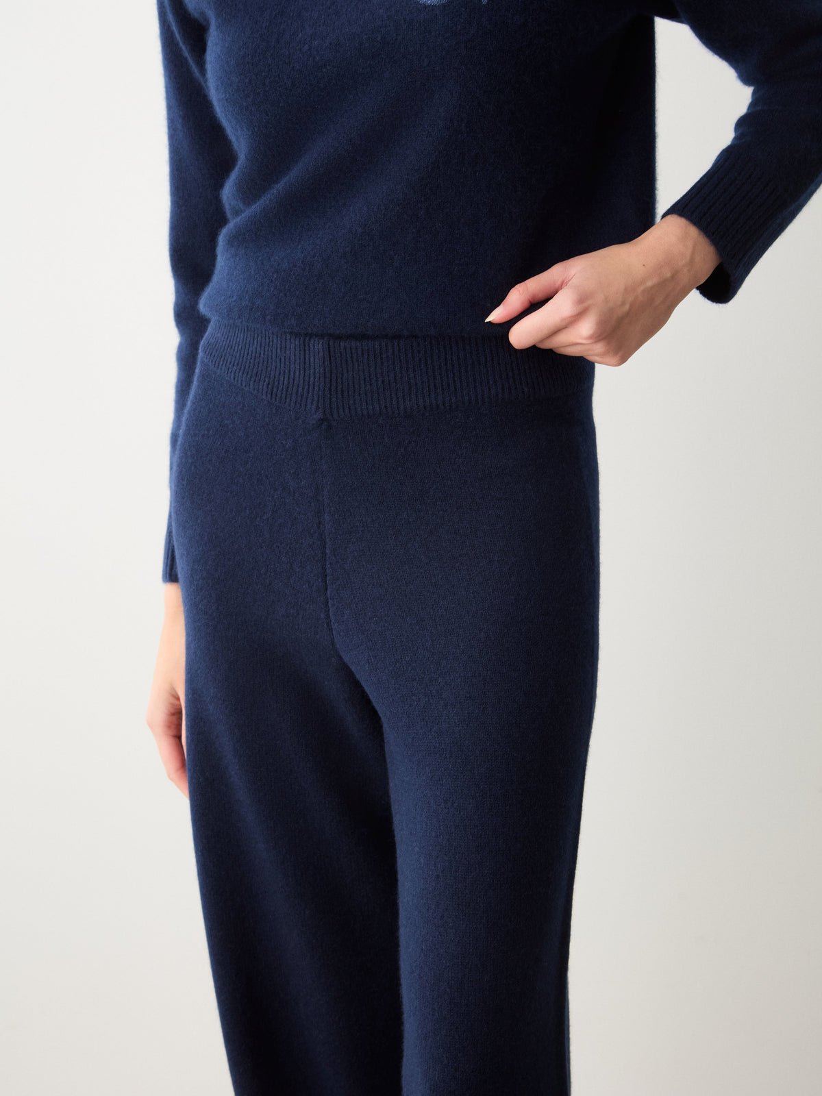 A person wears a matching sweater and dark navy Monogram Jogger Women cashmere pants designed as luxury loungewear with an elasticized waistband.