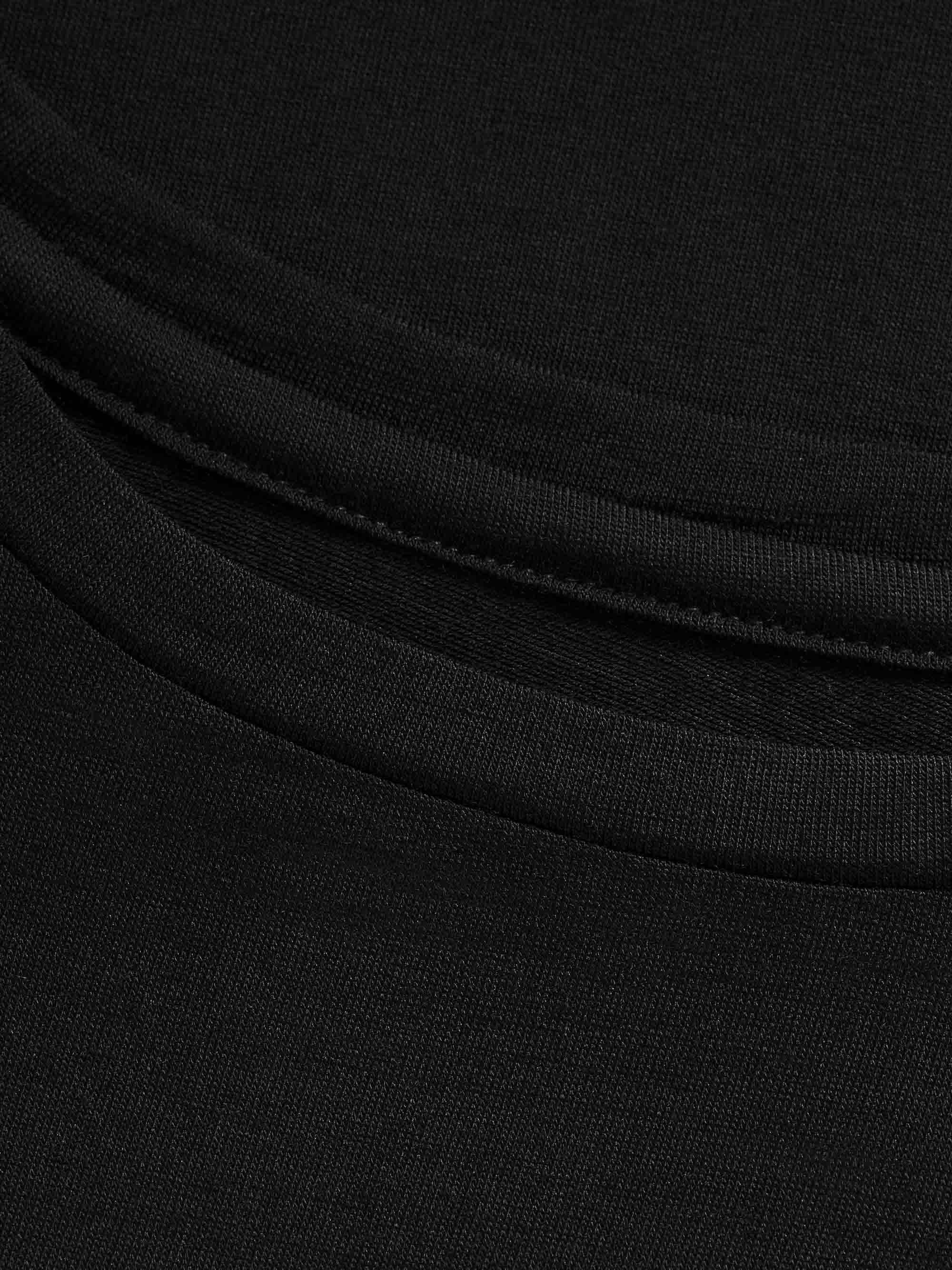 Close-up of a black fabric, revealing the stitching on a garment. The material appears to be a soft, knit texture with a neatly finished hem. The fabric is gathered slightly, showcasing the quality and attention to detail in the construction of the Natt LongSleeve PJ Women Black by We Norwegians.