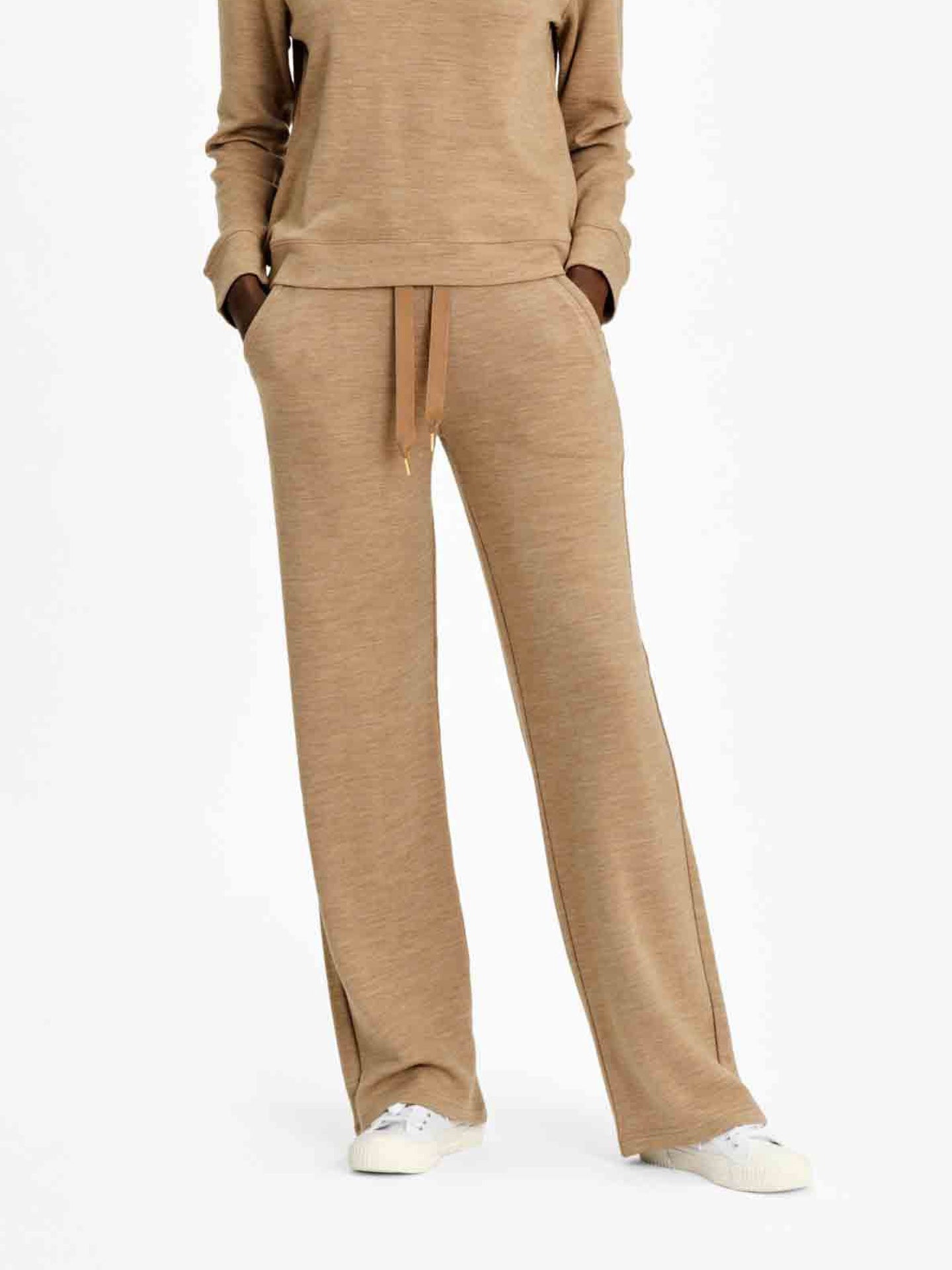 A person is dressed in the Limited Time Bundle: Tind Crewneck & Tind Straight Leg Pant Women by We Norwegians. With just the lower half of their body visible and hands tucked in pockets, they pair their outfit with white sneakers, creating a relaxed and comfortable look ideal for any casual outing.