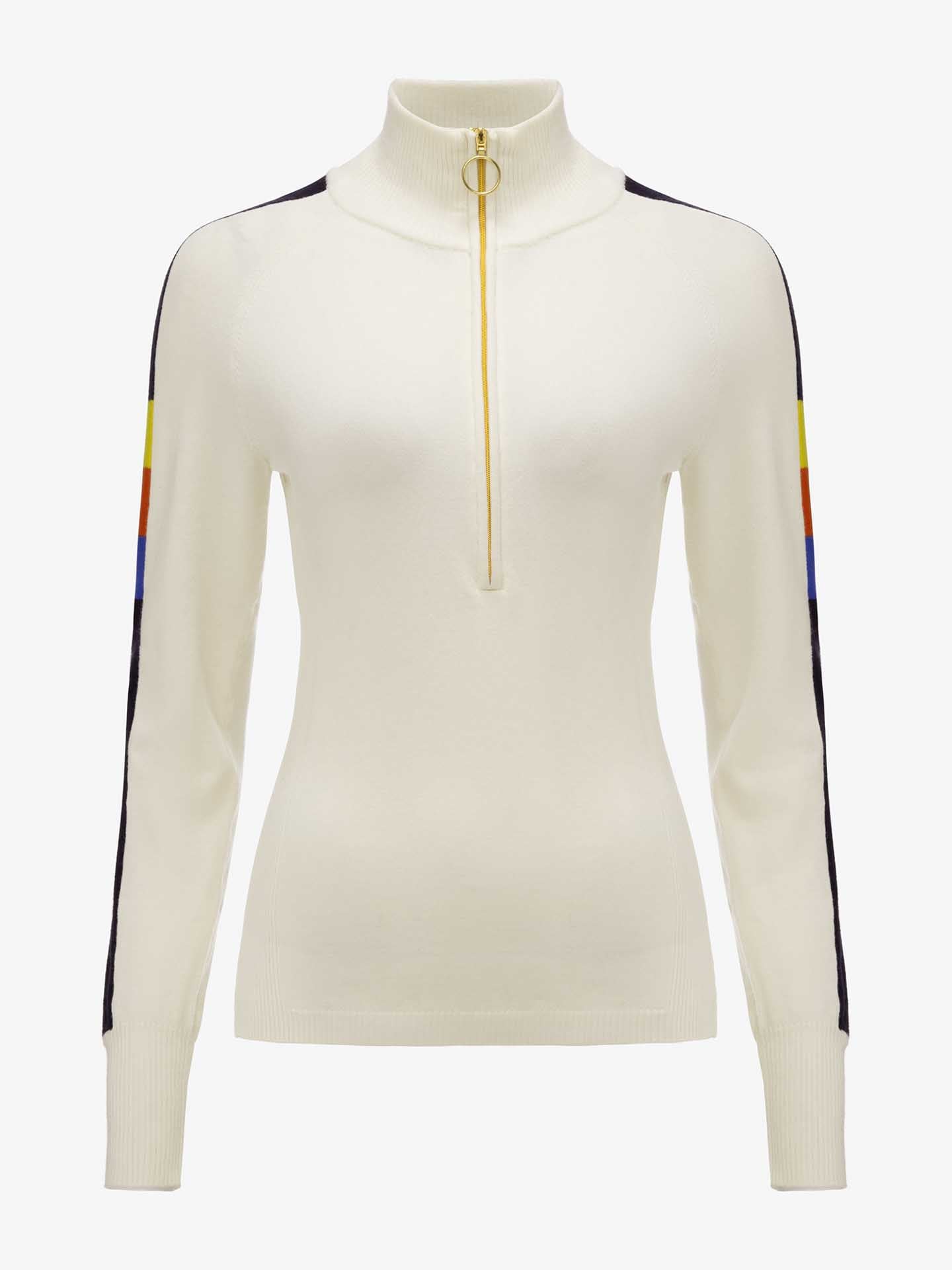 The Varden Zip Up Women by We Norwegians is a cream-colored women's ski sweater with long sleeves and a high collar, adorned with a gold ring zipper on the front. This 70s-inspired design features black strips running down the top of each sleeve, complemented by small segments of blue, yellow, and red color blocks near the shoulders.