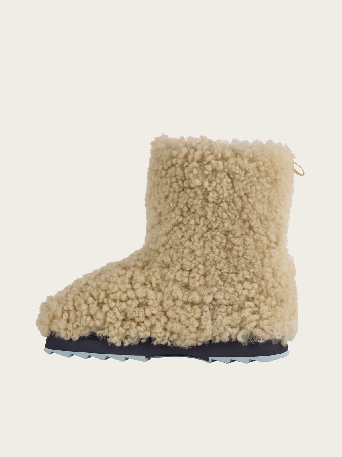 A single cream-colored, fluffy boot from We Norwegians’ EMU x WN Sharky Lo Teddy collection, crafted from plush Australian sheepskin with a thick, curly wool texture and a dark, ridged sole, is shown in profile against a plain light background—exuding cozy style and comfort.